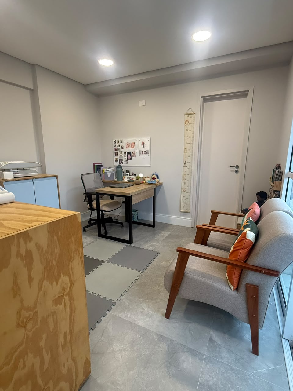 Consultório com mesa de atendimento, régua de crescimento e tapete emborrachado para as crianças