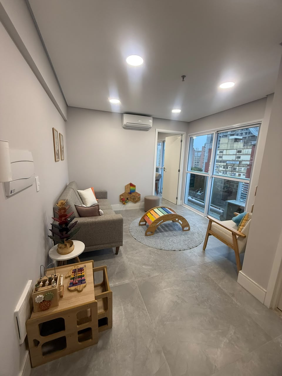 Ambiente de espera amplo e iluminado, com sofá confortável e vista para a cidade