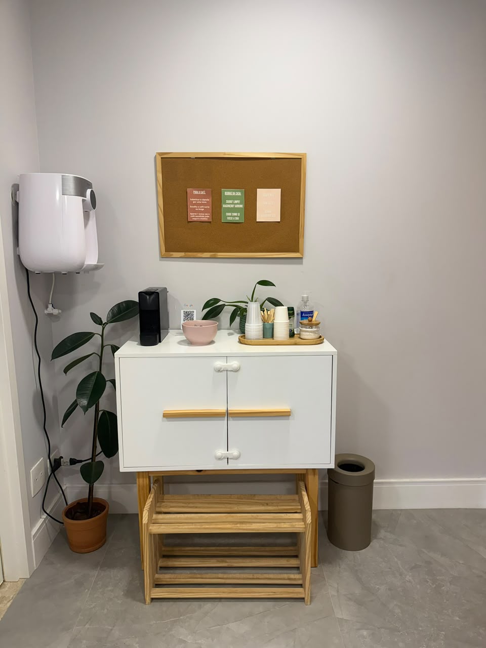 Cantinho do café com cafeteira, água e mural de recados para quem acompanha